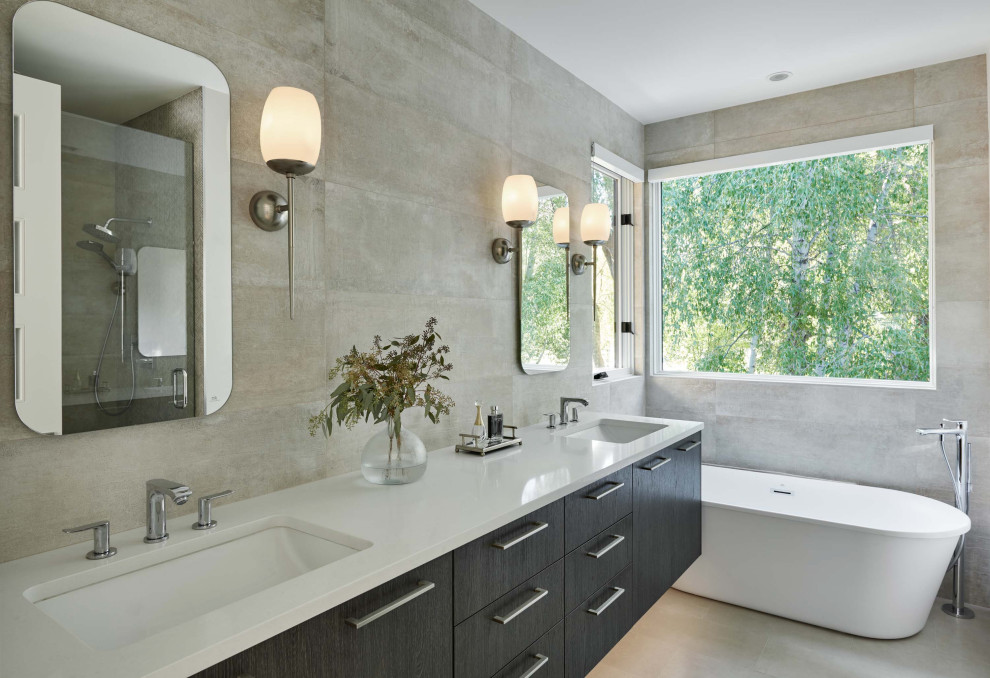 This is an example of a mid-sized contemporary master bathroom in Denver with flat-panel cabinets, dark wood cabinets, a freestanding tub, an alcove shower, a two-piece toilet, gray tile, porcelain tile, porcelain floors, a drop-in sink, engineered quartz benchtops, a hinged shower door, white benchtops, grey floor, a double vanity and a floating vanity.