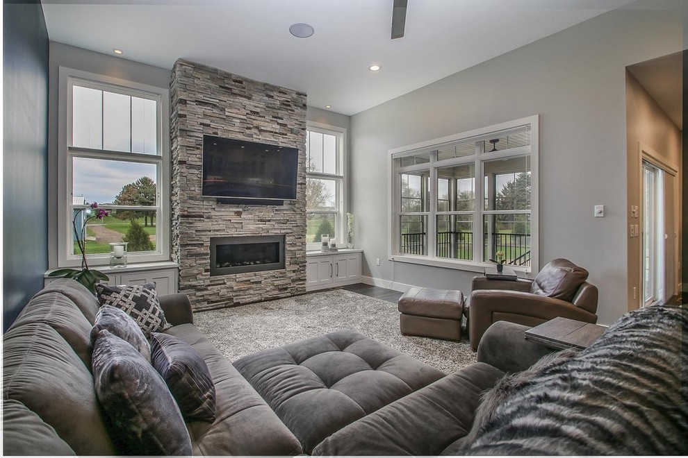 Photo of a large transitional open concept living room in Other with grey walls, medium hardwood floors, a ribbon fireplace, a stone fireplace surround, a wall-mounted tv and brown floor.