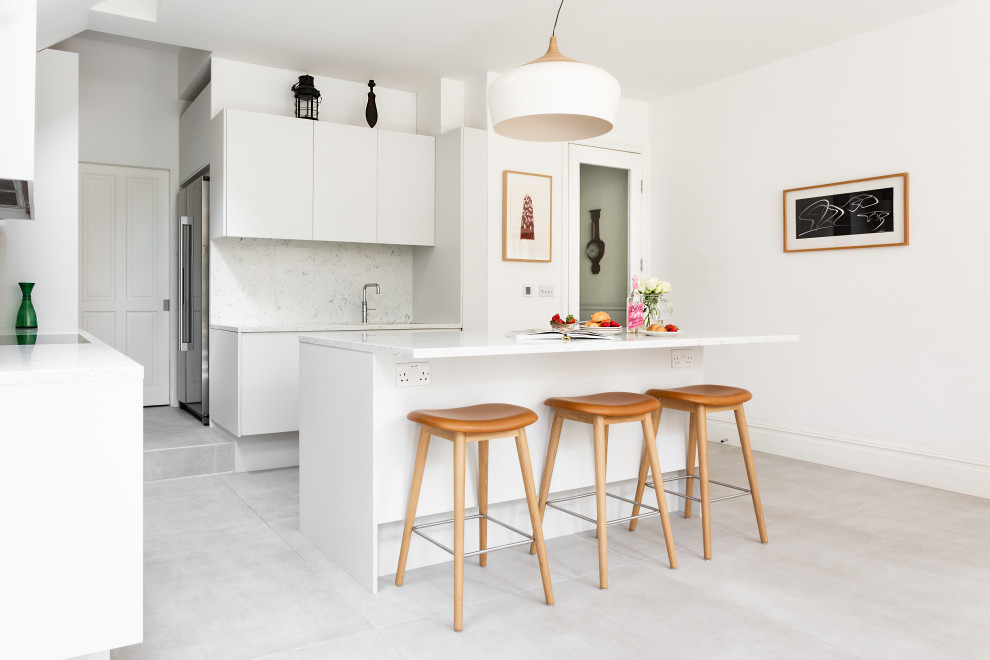 Design ideas for a mid-sized contemporary open plan kitchen in London with an integrated sink, flat-panel cabinets, white cabinets, marble benchtops, white splashback, marble splashback, stainless steel appliances, ceramic floors, with island, white floor and white benchtop.