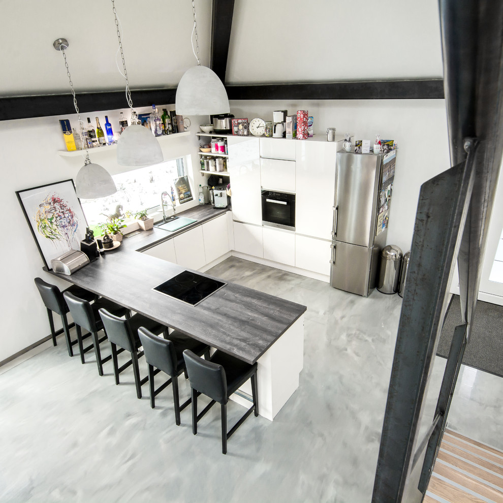 Inredning av ett modernt stort kök, med släta luckor, vita skåp, träbänkskiva, en halv köksö och grått golv