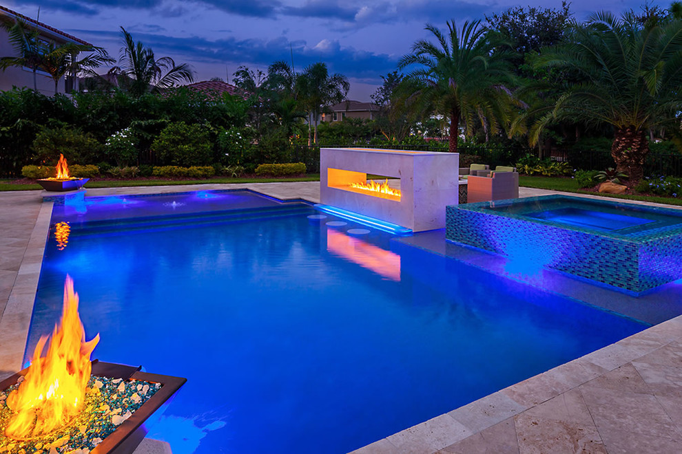 Photo of a large tropical backyard custom-shaped lap pool in Miami with a hot tub and tile.