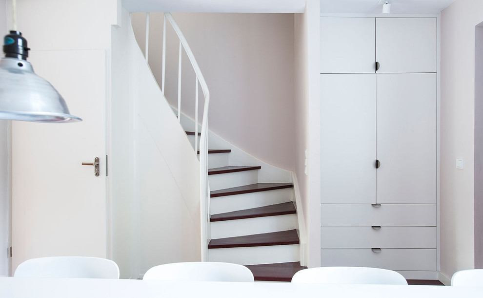 This is an example of a mid-sized country wood curved staircase in Frankfurt with wood risers and wood railing.
