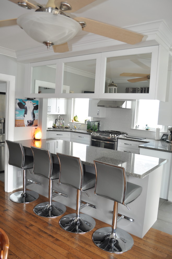 Small transitional u-shaped porcelain tile and gray floor eat-in kitchen photo in Toronto with an undermount sink, shaker cabinets, white cabinets, quartz countertops, white backsplash, porcelain backsplash, stainless steel appliances and an island