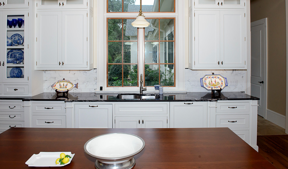 Inspiration for a medium tone wood floor kitchen remodel in Atlanta with an undermount sink, marble countertops, white backsplash, stainless steel appliances and an island