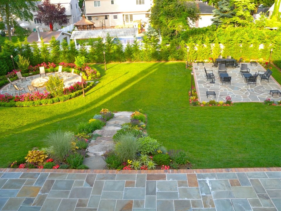 Photo of a mid-sized traditional backyard partial sun formal garden in New York with natural stone pavers.