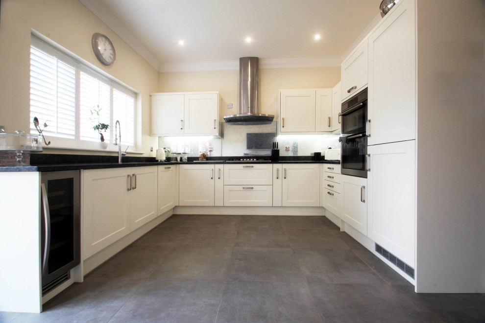 Inspiration for a mid-sized traditional u-shaped separate kitchen in Cheshire with a drop-in sink, shaker cabinets, white cabinets, granite benchtops, black splashback, glass tile splashback, stainless steel appliances, slate floors, no island, grey floor and black benchtop.