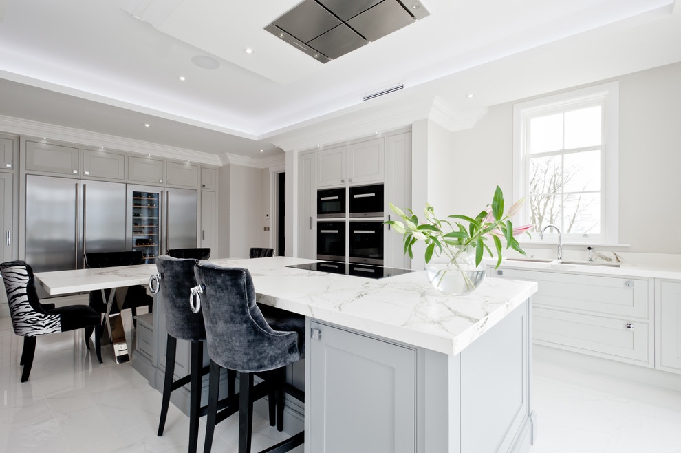 Large transitional eat-in kitchen in Kent with an undermount sink, beaded inset cabinets, grey cabinets, solid surface benchtops, panelled appliances, with island and grey floor.