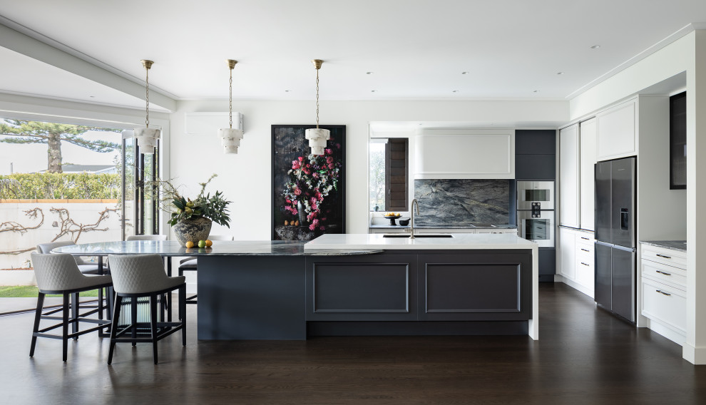 Photo of a transitional l-shaped eat-in kitchen in Auckland with an undermount sink, blue cabinets, quartzite benchtops, blue splashback, stone slab splashback, stainless steel appliances, dark hardwood floors, with island, brown floor and blue benchtop.