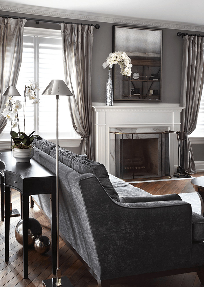 Inspiration for a mid-sized transitional formal enclosed living room in Paris with grey walls, medium hardwood floors, a standard fireplace, a plaster fireplace surround and a freestanding tv.
