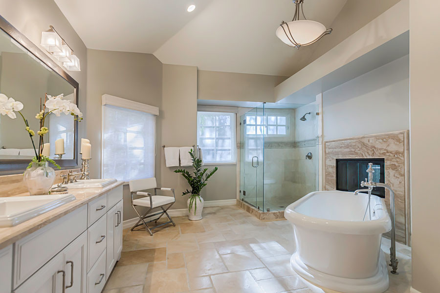 Inspiration for a large transitional master bathroom in Los Angeles with a drop-in sink, furniture-like cabinets, white cabinets, limestone benchtops, a freestanding tub, an open shower, a two-piece toilet, beige tile, stone slab, grey walls and travertine floors.