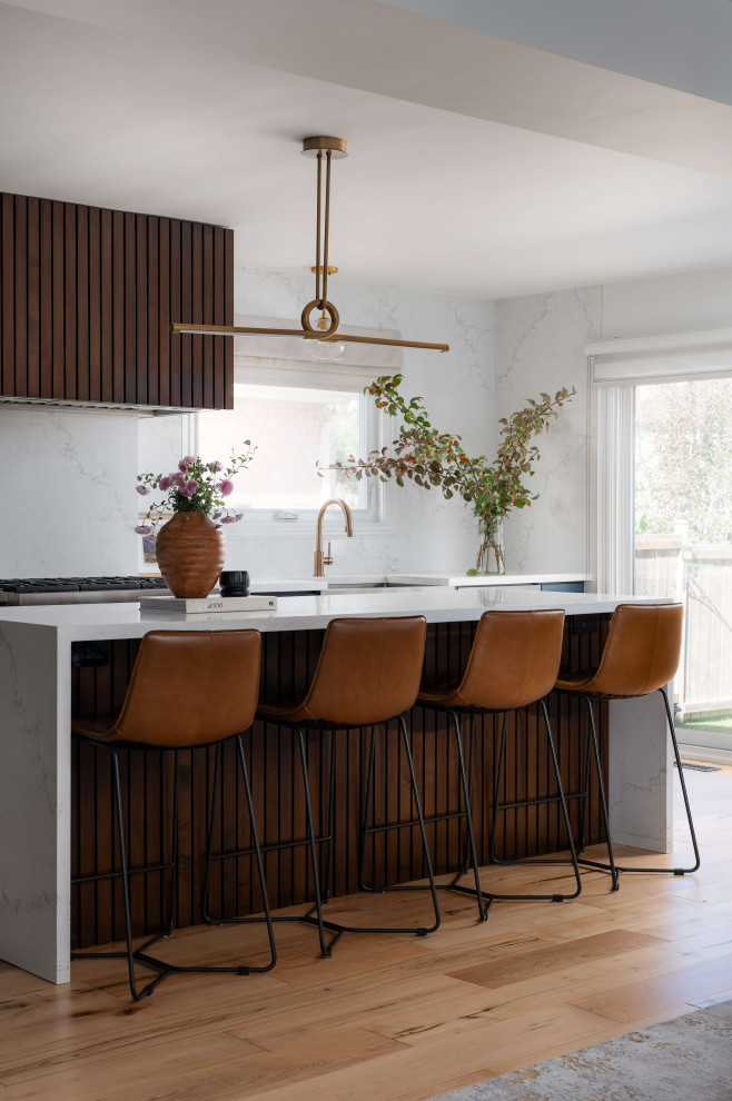 Inspiration for a mid-sized transitional l-shaped medium tone wood floor and beige floor eat-in kitchen remodel in Toronto with a farmhouse sink, shaker cabinets, blue cabinets, quartz countertops, white backsplash, quartz backsplash, stainless steel appliances, an island and white countertops