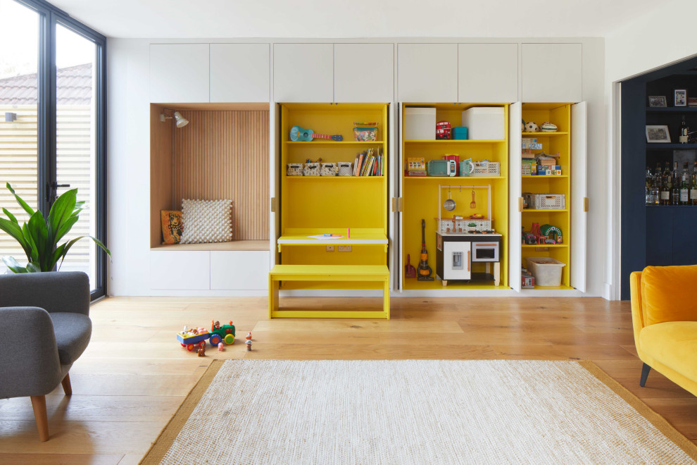 Источник вдохновения для домашнего уюта: большая открытая гостиная комната в современном стиле с с книжными шкафами и полками, желтыми стенами, паркетным полом среднего тона, панелями на части стены и акцентной стеной без камина