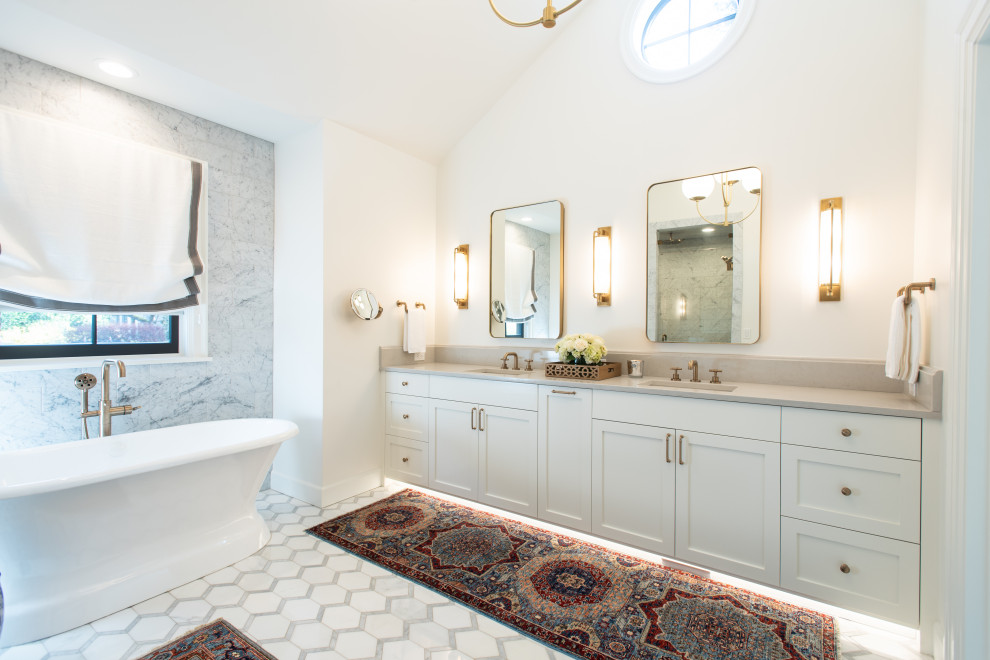 Idée de décoration pour une grande salle de bain principale tradition avec un placard à porte shaker, des portes de placard blanches, meuble double vasque, meuble-lavabo suspendu, un bain bouillonnant, un carrelage blanc, un mur blanc, un lavabo posé et un plan de toilette gris.