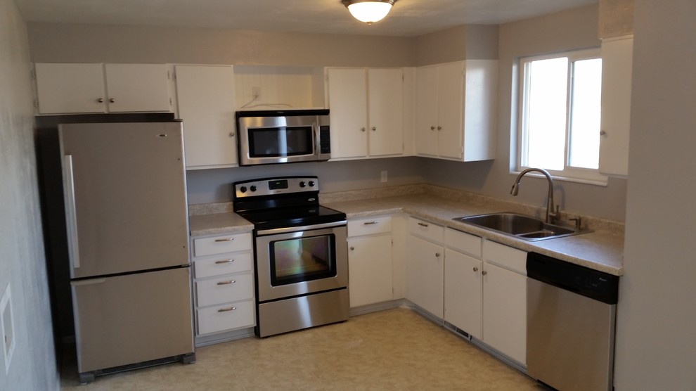 Mid-sized transitional l-shaped eat-in kitchen in Salt Lake City with a double-bowl sink, flat-panel cabinets, white cabinets, laminate benchtops, stainless steel appliances, linoleum floors and no island.