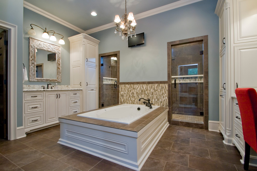 This is an example of a large country master bathroom in Little Rock with raised-panel cabinets, white cabinets, a double shower, blue walls, an undermount sink, granite benchtops, a drop-in tub, beige tile, brown tile, matchstick tile, slate floors, brown floor and a hinged shower door.