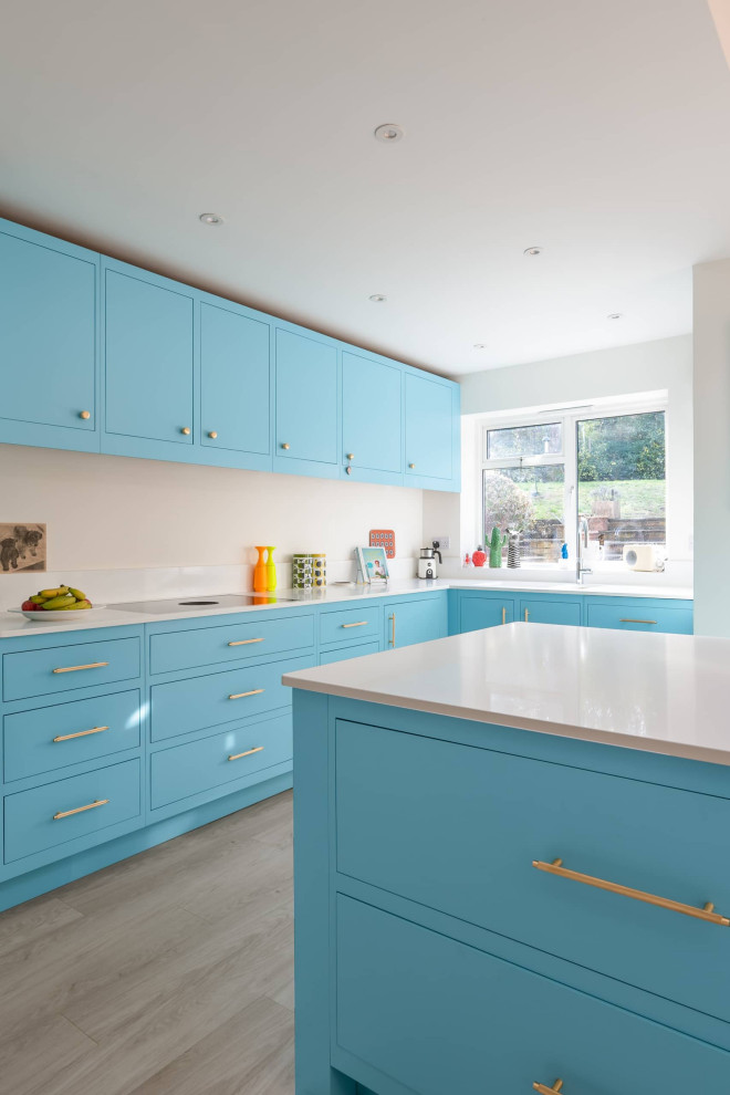 Immagine di una cucina moderna di medie dimensioni con lavello da incasso, ante lisce, ante blu, top in quarzite, paraspruzzi bianco e elettrodomestici neri