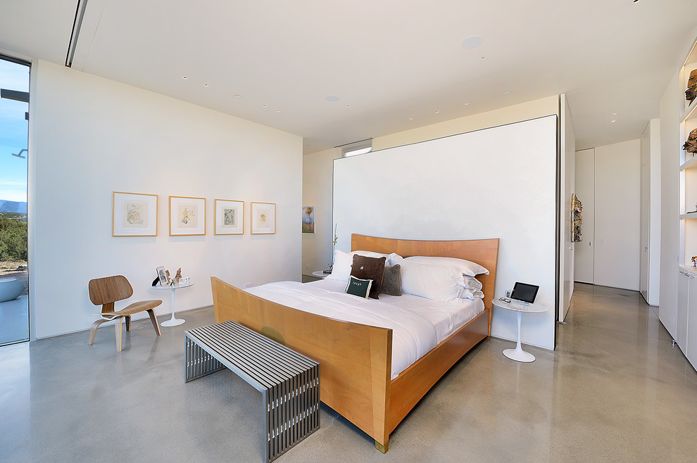Modern master bedroom in Other with white walls, concrete floors, no fireplace and grey floor.