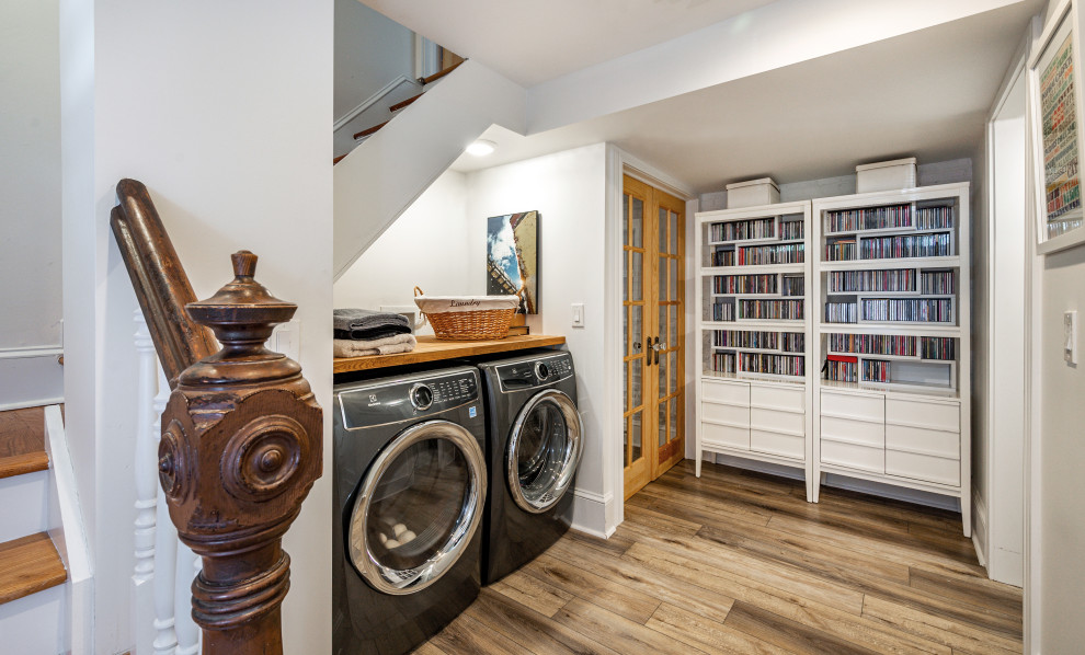 Foto di una piccola lavanderia eclettica con top in legno, pareti bianche, pavimento in vinile, lavatrice e asciugatrice affiancate, pavimento marrone e top marrone