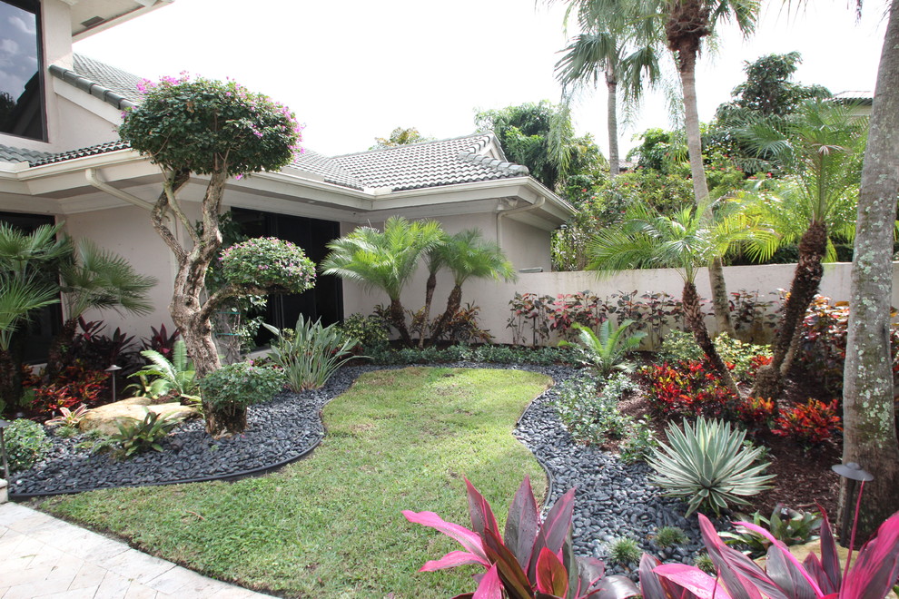 This is an example of a mid-sized contemporary front yard full sun garden in Tampa with natural stone pavers.