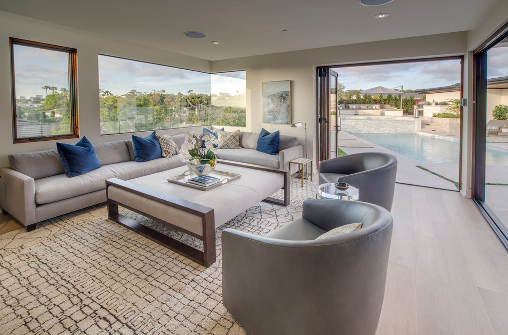 This is an example of a large contemporary open concept family room in Orange County with white walls, light hardwood floors, no fireplace and no tv.