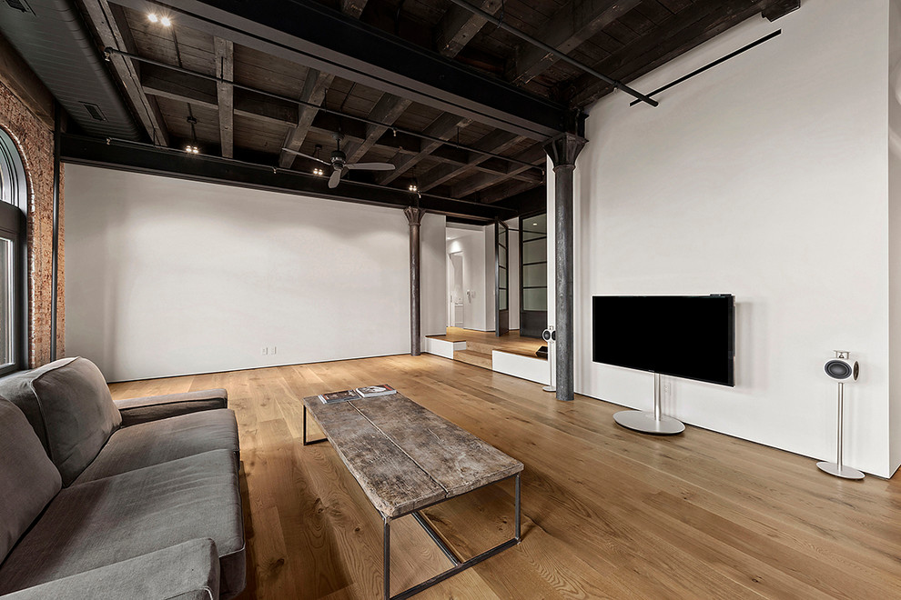 Industrial open concept family room in New York with white walls, light hardwood floors, no fireplace and a freestanding tv.