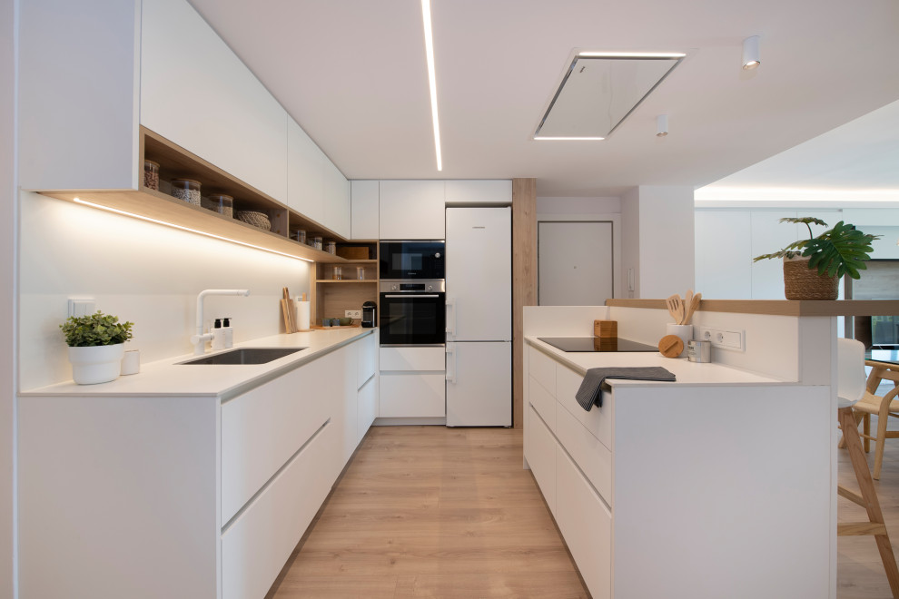 Exempel på ett mellanstort nordiskt vit vitt kök, med en undermonterad diskho, släta luckor, vita skåp, bänkskiva i kvarts, vitt stänkskydd, rostfria vitvaror, mellanmörkt trägolv, en köksö och brunt golv