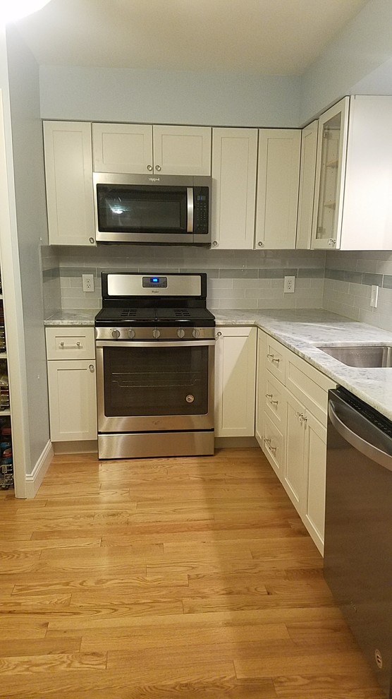 Small beach style l-shaped eat-in kitchen in Cleveland with an undermount sink, shaker cabinets, white cabinets, quartzite benchtops, grey splashback, glass tile splashback, stainless steel appliances, light hardwood floors, no island and blue benchtop.