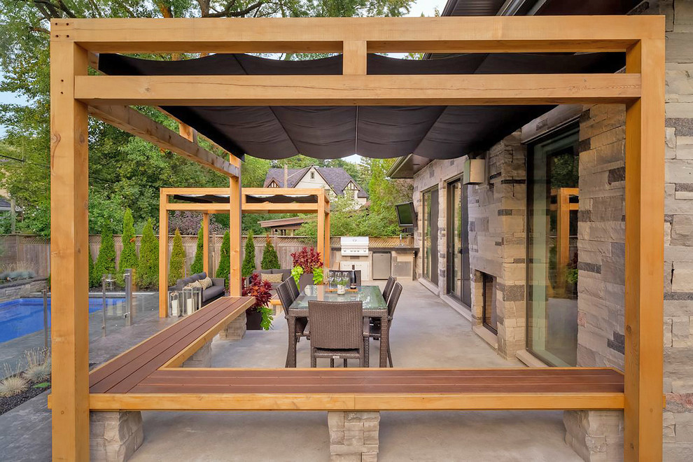 This is an example of a modern backyard deck in Toronto with a fire feature and a pergola.