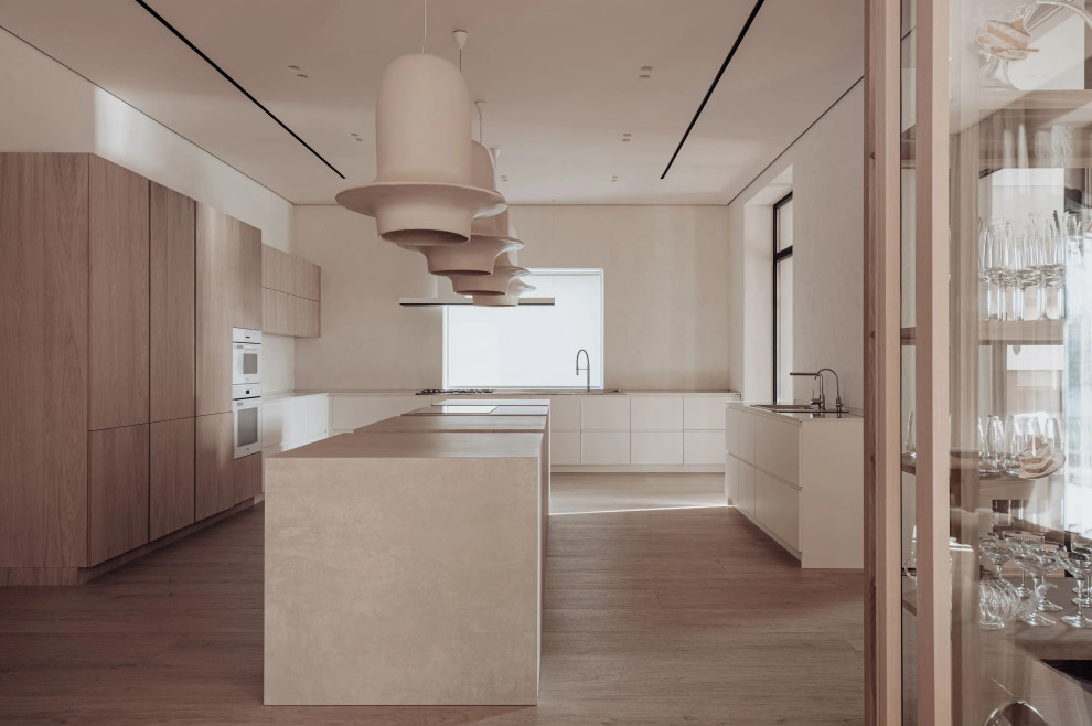 Esempio di una cucina scandinava di medie dimensioni con lavello a tripla vasca, ante lisce, ante in legno chiaro, parquet chiaro, 2 o più isole e pavimento marrone