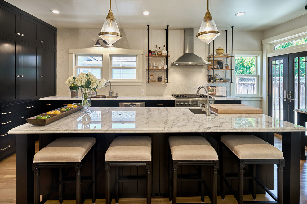 This is an example of a mid-sized transitional single-wall separate kitchen in San Francisco with an undermount sink, shaker cabinets, black cabinets, marble benchtops, subway tile splashback, stainless steel appliances, light hardwood floors and with island.