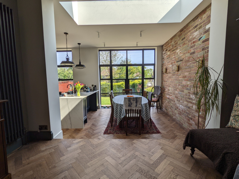 Cette photo montre une grande salle à manger ouverte sur la cuisine chic avec parquet clair, une cheminée standard et un sol marron.
