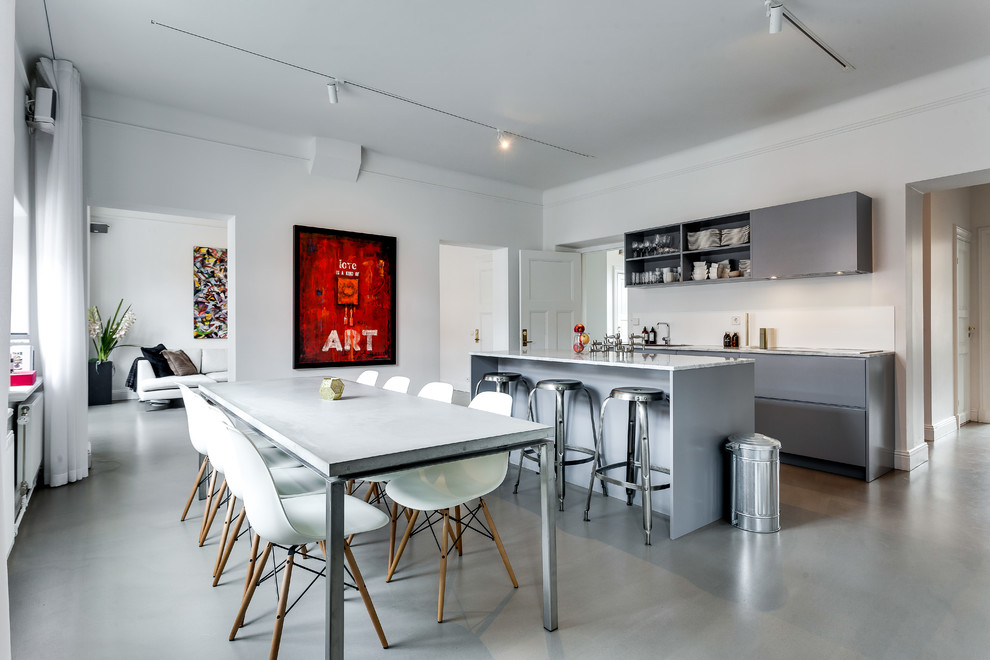 This is an example of a mid-sized scandinavian galley eat-in kitchen in Stockholm with flat-panel cabinets, grey cabinets, stainless steel appliances, concrete floors, with island and marble benchtops.
