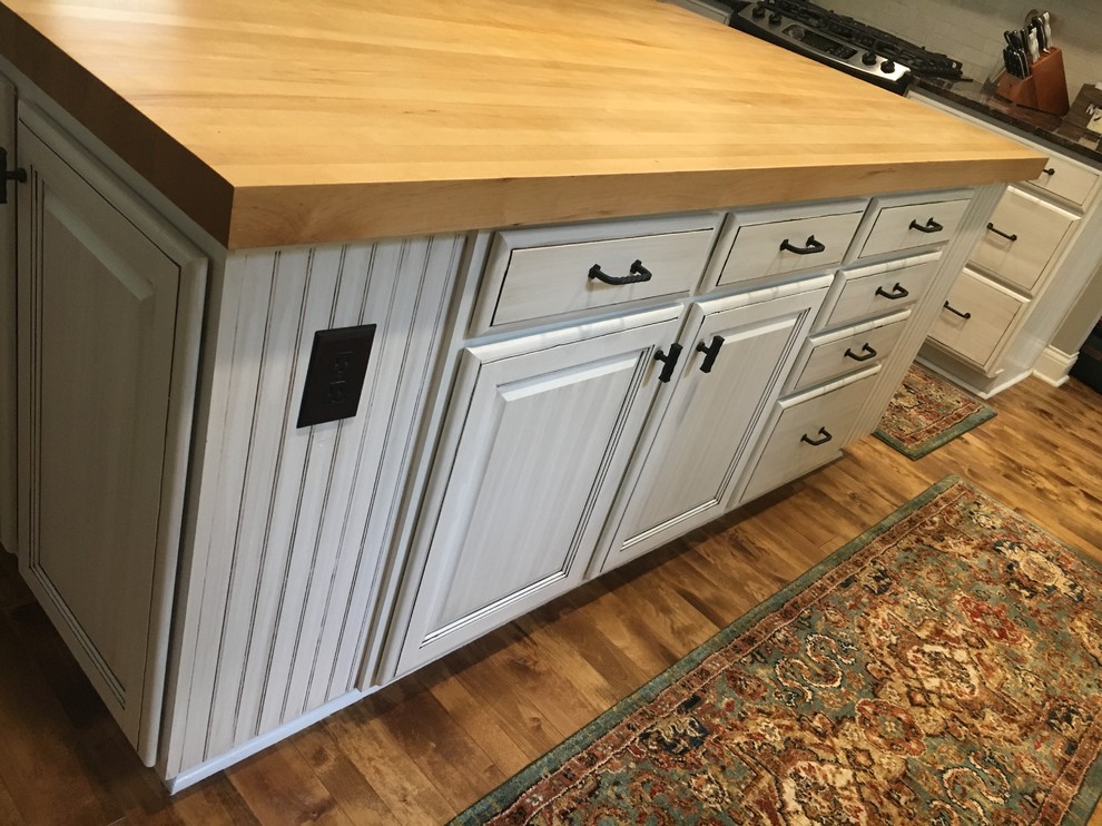 Inspiration for a mid-sized rustic l-shaped light wood floor and brown floor eat-in kitchen remodel in Indianapolis with an undermount sink, shaker cabinets, white cabinets, quartzite countertops, gray backsplash, travertine backsplash, stainless steel appliances, an island and black countertops