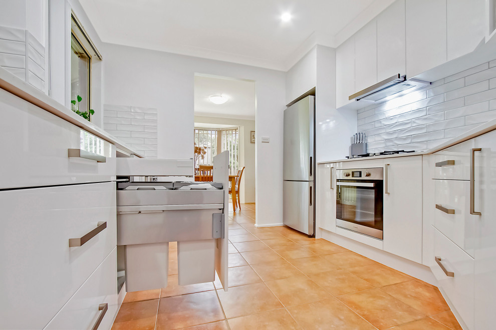 Inspiration for a medium sized modern kitchen/diner in Sydney with a built-in sink, flat-panel cabinets, white cabinets, engineered stone countertops, white splashback, metro tiled splashback, stainless steel appliances and white worktops.