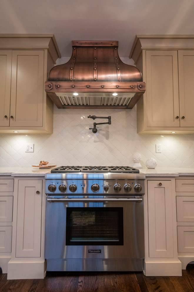 Mid-sized traditional eat-in kitchen in Indianapolis with a farmhouse sink, beaded inset cabinets, beige cabinets, quartzite benchtops, beige splashback, porcelain splashback, stainless steel appliances, medium hardwood floors, a peninsula and brown floor.