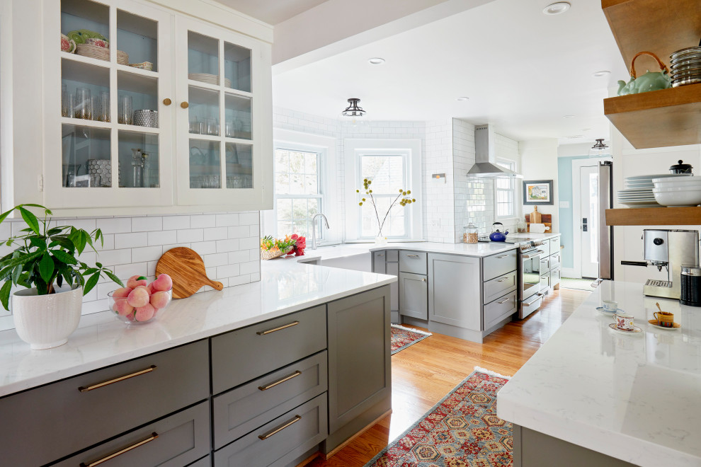 Mid-sized transitional galley medium tone wood floor and brown floor eat-in kitchen photo with a farmhouse sink, shaker cabinets, gray cabinets, quartz countertops, white backsplash, subway tile backsplash, stainless steel appliances, no island and white countertops