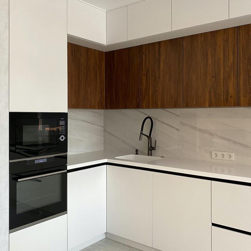 Inspiration for a large contemporary l-shaped eat-in kitchen in Moscow with an integrated sink, flat-panel cabinets, white cabinets, solid surface benchtops, grey splashback, porcelain splashback, black appliances, laminate floors, no island, turquoise floor and white benchtop.