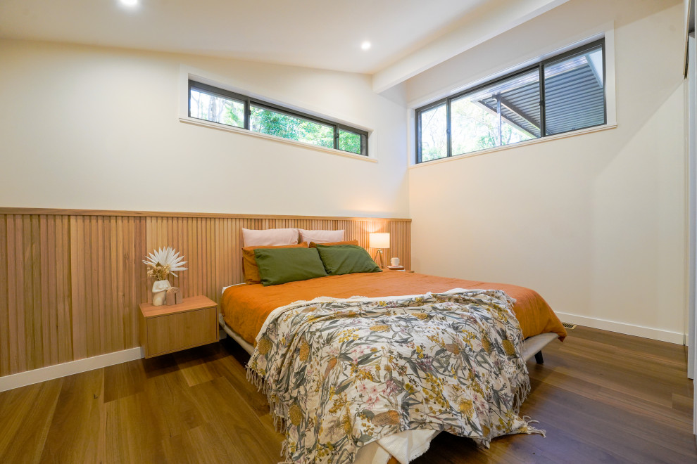 Foto di una camera degli ospiti minimal di medie dimensioni con pareti multicolore, pavimento in legno massello medio, pavimento marrone, soffitto a volta e boiserie