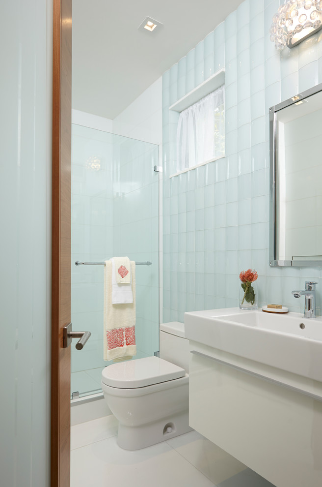 Photo of a mid-sized contemporary kids bathroom in Miami with beaded inset cabinets, white cabinets, a corner shower, a two-piece toilet, white tile, glass tile, white walls, marble floors, an integrated sink and solid surface benchtops.