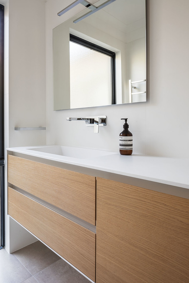 This is an example of a mid-sized contemporary master bathroom in Perth with light wood cabinets, white tile, white walls, ceramic floors, an integrated sink, solid surface benchtops, beige floor and a hinged shower door.