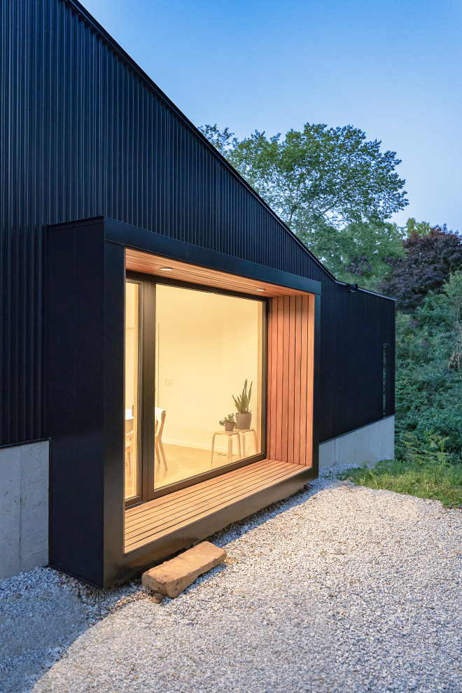 Réalisation d'une petite façade de maison métallique et noire design à un étage avec un toit plat et un toit noir.