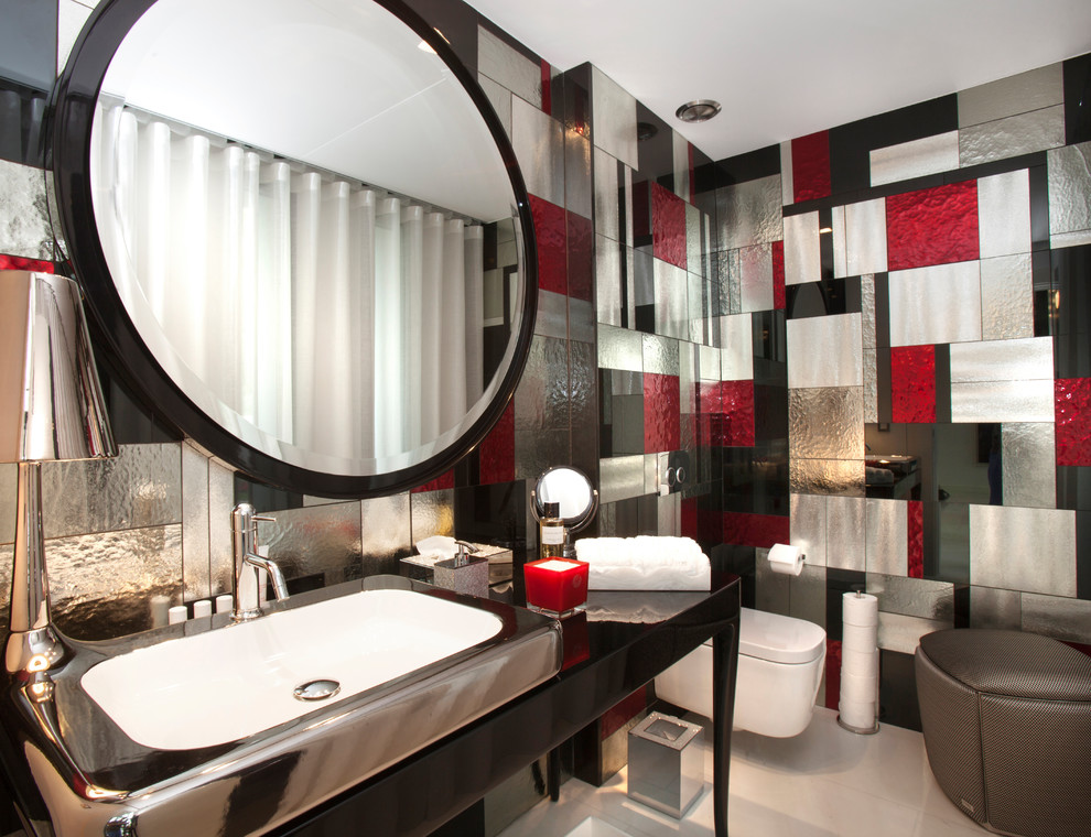 This is an example of a contemporary powder room in Nice with furniture-like cabinets, black cabinets, a wall-mount toilet, multi-coloured tile, multi-coloured walls and white floor.