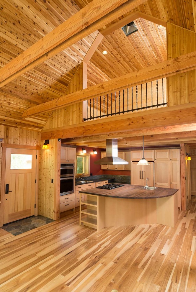 Example of an arts and crafts light wood floor open concept kitchen design with stainless steel appliances and an island