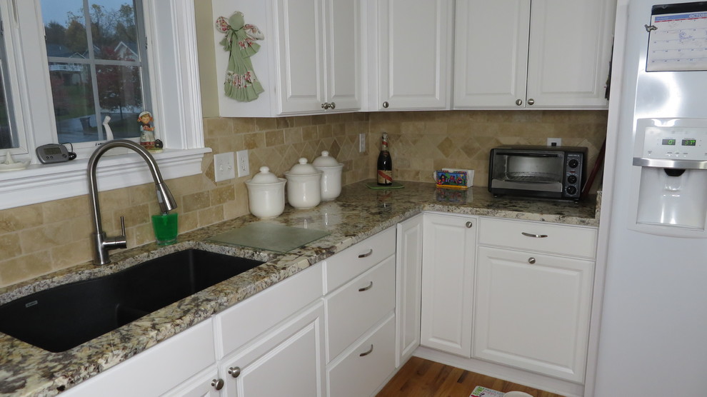 Example of a mid-sized classic u-shaped kitchen design with an undermount sink, raised-panel cabinets, white cabinets, granite countertops, multicolored backsplash, travertine backsplash, white appliances and multicolored countertops
