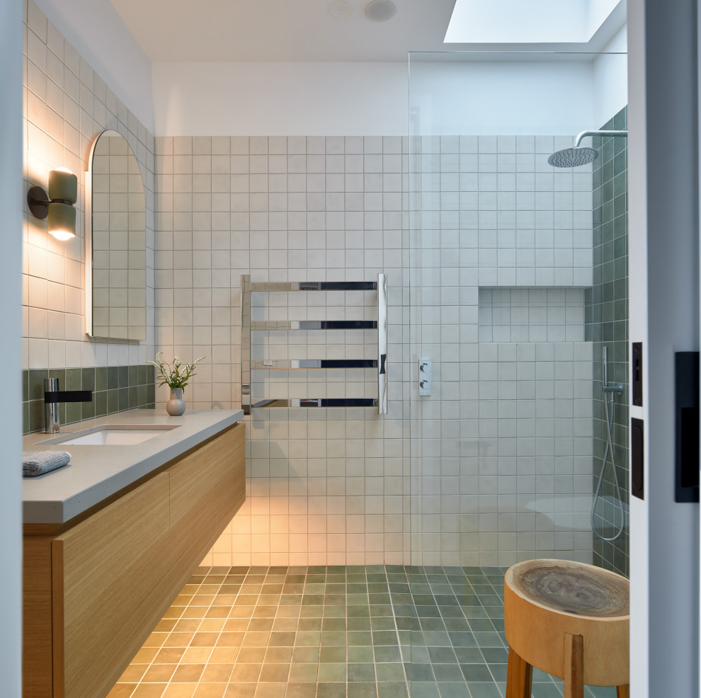 Immagine di una stanza da bagno design di medie dimensioni con ante lisce, ante in legno chiaro, piastrelle verdi, piastrelle in ceramica, pavimento con piastrelle in ceramica, lavabo sottopiano, top in superficie solida, pavimento verde, top grigio, un lavabo e mobile bagno sospeso