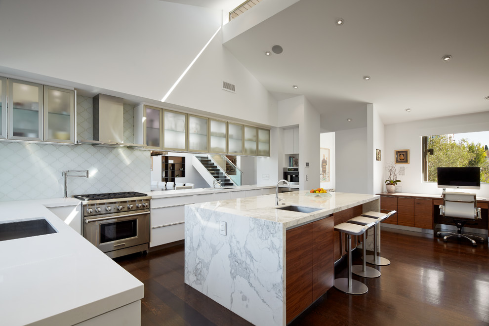 This is an example of a contemporary l-shaped kitchen in Los Angeles with an undermount sink, flat-panel cabinets, white cabinets, white splashback, glass tile splashback, stainless steel appliances, dark hardwood floors and with island.
