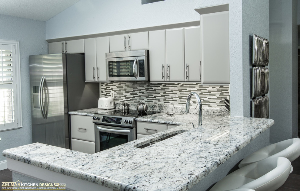 This is an example of a small contemporary l-shaped eat-in kitchen in Orlando with an undermount sink, flat-panel cabinets, grey cabinets, granite benchtops, multi-coloured splashback, mosaic tile splashback, stainless steel appliances and a peninsula.