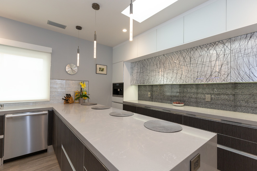 Photo of a mid-sized modern u-shaped separate kitchen in San Francisco with an undermount sink, flat-panel cabinets, grey cabinets, quartz benchtops, metallic splashback, glass tile splashback, stainless steel appliances, medium hardwood floors, a peninsula, brown floor and grey benchtop.