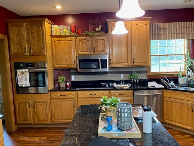 Open concept kitchen - large transitional l-shaped laminate floor and brown floor open concept kitchen idea with an undermount sink, flat-panel cabinets, white cabinets, quartz countertops, white backsplash, ceramic backsplash, stainless steel appliances, an island and white countertops