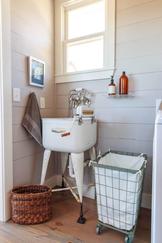 Design ideas for a small country laundry cupboard in Austin with an utility sink, grey walls, medium hardwood floors and brown floor.